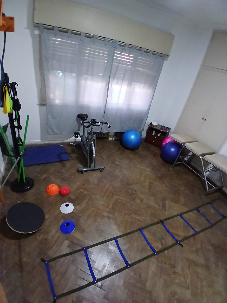Sala de ejercicio terapéutico con pelotas, bicicleta fija y bandas